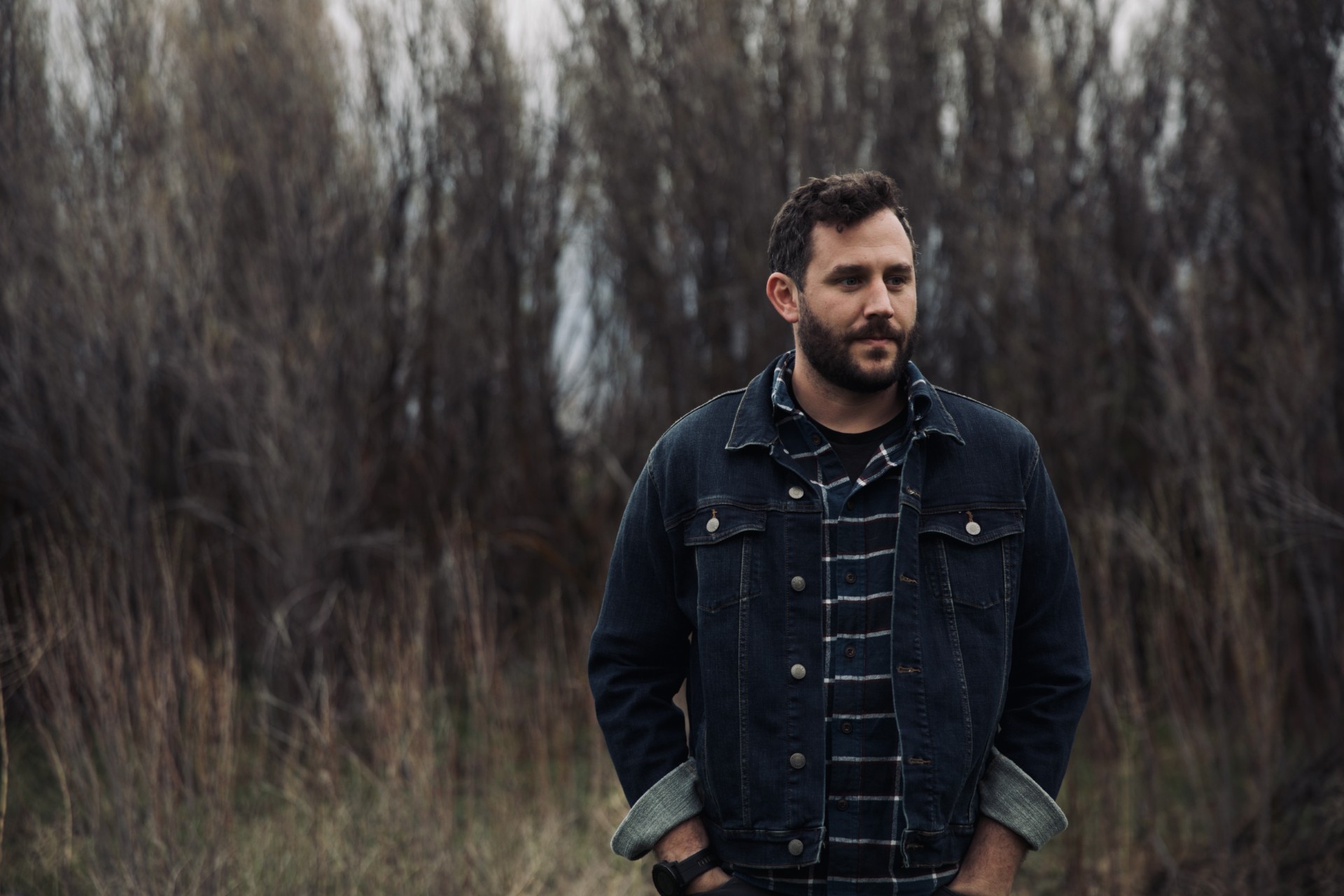 Riley Wilkinson outdoors in a denim jacket among bare winter trees