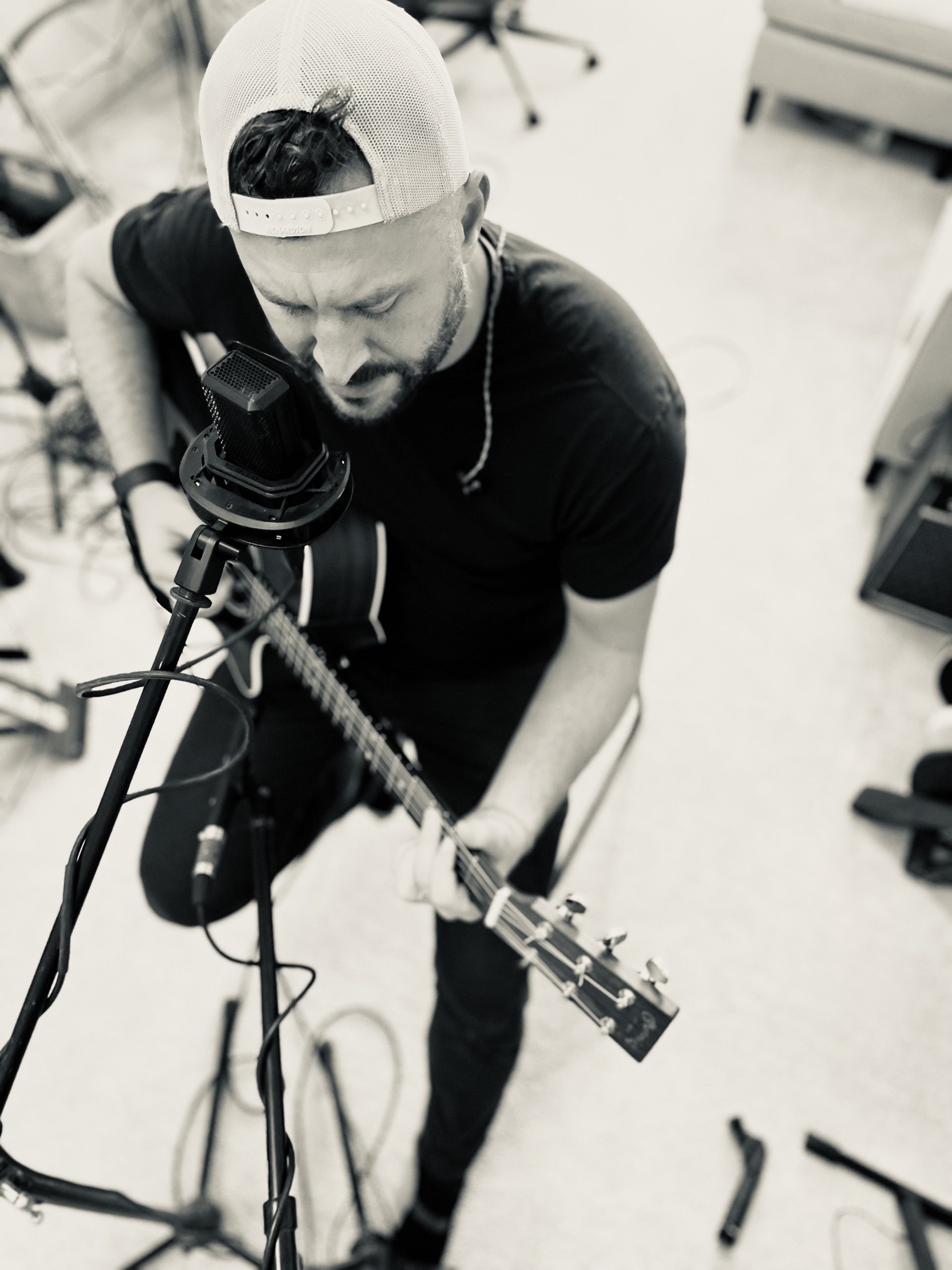 Riley Wilkinson tracking vocals over an acoustic guitar, overhead view