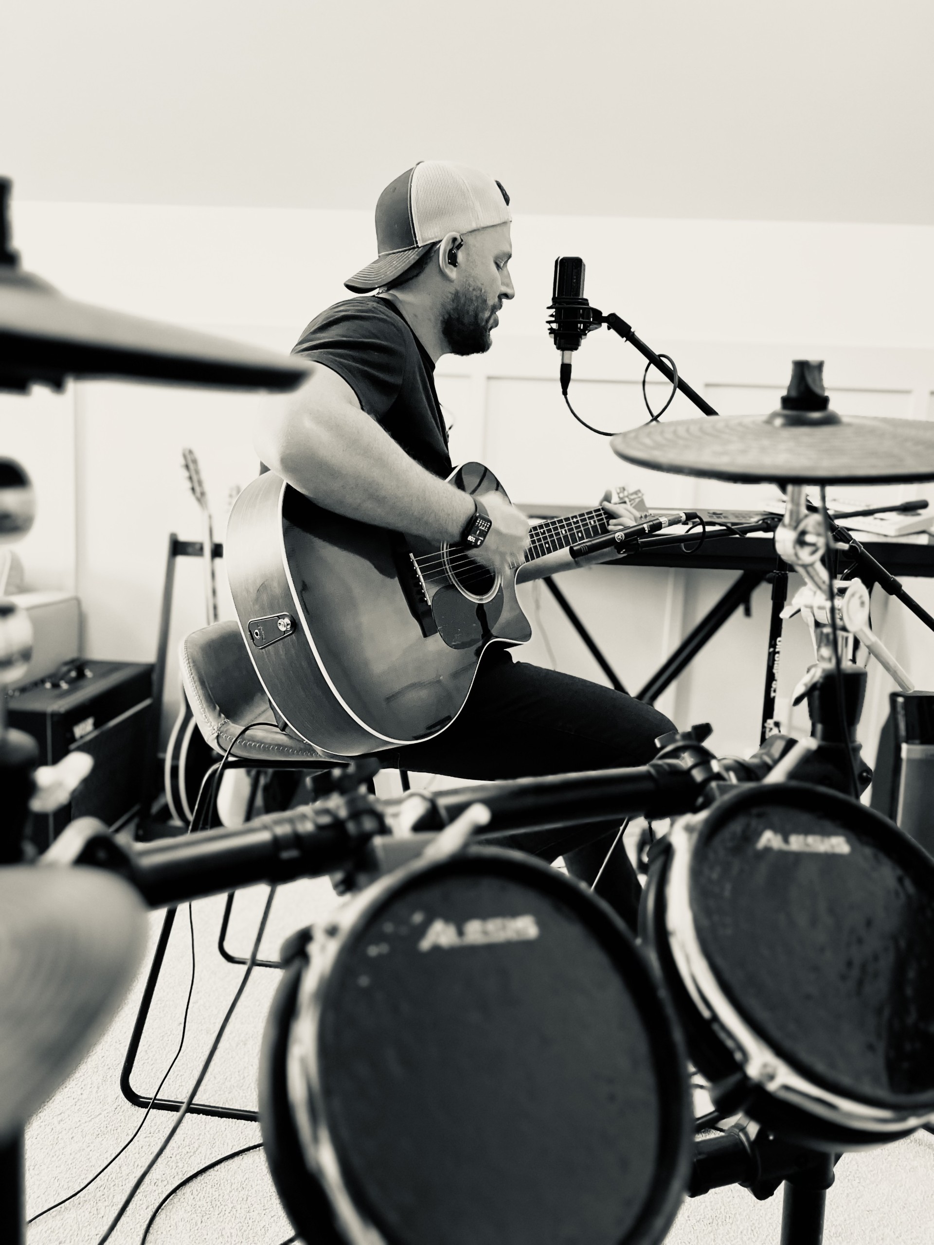 Riley Wilkinson playing acoustic guitar at a kit during a recording session
